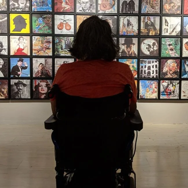 A wheelchair user viewing art in a gallery.